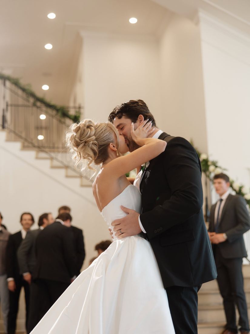 Bride with a voluminous textured updo kissing her groom at the ceremony